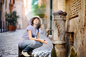 Young woman drinking clean water from the fountain in Rome, Italy