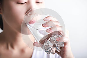 Young woman drinking clean water in her hand.