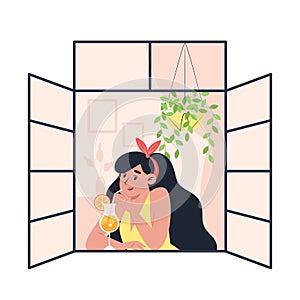 Young woman drinking cocktail at open window at home