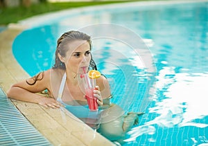 Young woman drinking cocktail in pool