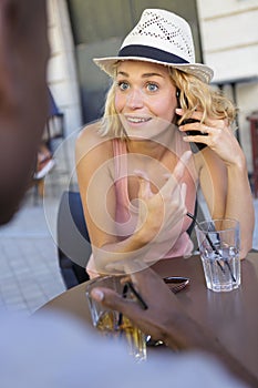 young woman drinking cocktail and taking call