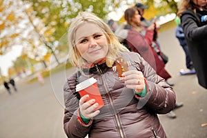 Young woman drinking coffe with ginger gingerbread in autumn time in park