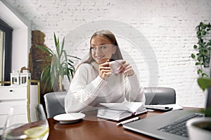 Young woman drinking coffe and looking through a window.