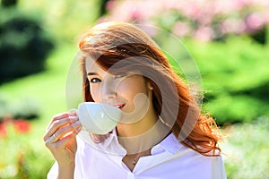 Young woman drinking coffe in spring pakr. Beautiful woman holding a coffee cup in her hand.