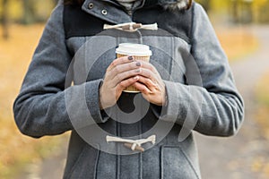 Young woman drinking coffee in an autumn park