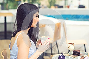 Side view of beautiful girl having coffee at cafe.