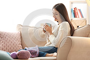 Young woman drinking coffee after knitting at home