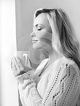 Young woman drinking coffee and looking it to the window