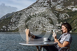 Young woman drinking coffee and using smarphone in the morning a