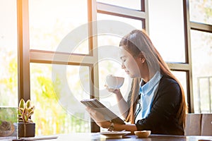 Young woman is drinking coffee with using tablet in coffee shop