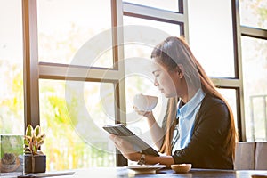 Young woman is drinking coffee with using tablet in coffee shop