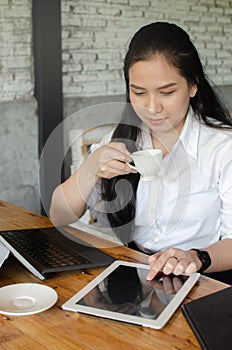 Young woman drinking coffee while working in cafe