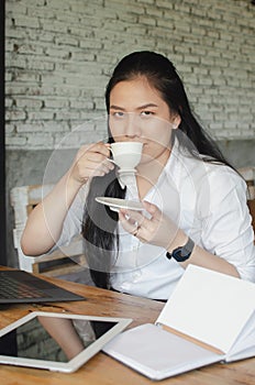 Young woman drinking coffee while working in cafe