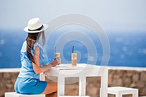 Young woman drinking cold coffee enjoying sea view.