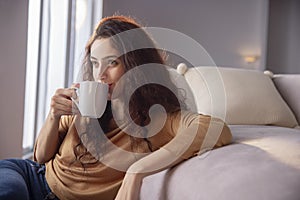 Young woman drinking cup of tea at home