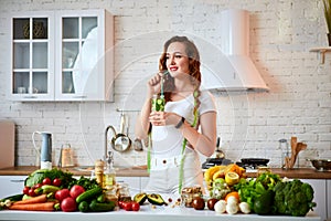 Young woman drinking fresh water with cucumber, lemon and leaves of mint from glass in the kitchen. Healthy Lifestyle and Eating.