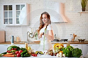 Young woman drinking fresh water with cucumber, lemon and leaves of mint from glass in the kitchen. Healthy Lifestyle and Eating.