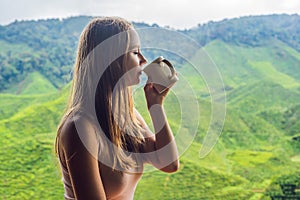 Young woman Drinking Healthy Green Tea against a tea plantation.