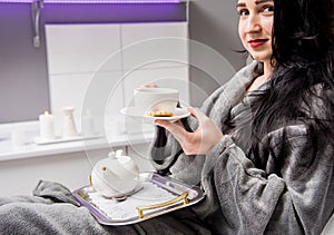 Young woman drinking herbal tea after spa procedures.