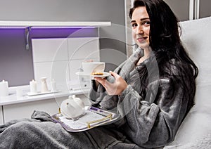 Young woman drinking herbal tea after spa procedures.