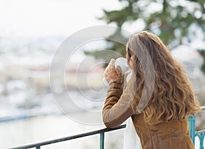 Young woman drinking hot beverage in winter park