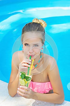 Young woman drinking lemonade in the pool