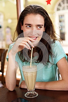 Young woman drinking milkshake at a cafe