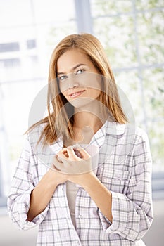 Young woman drinking morning tea in pyjama smiling