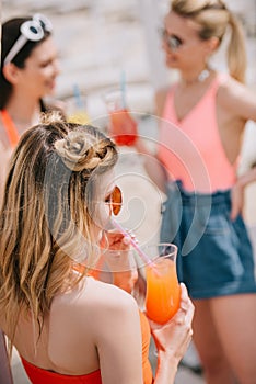 young woman drinking summer cocktail while spending time with girlfriend