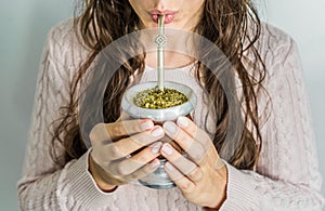 Young woman drinking traditional Argentinian yerba mate tea.