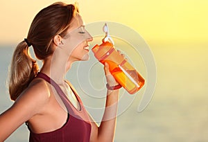 Young woman drinking water from bottle after fitness exercises