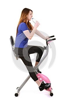Young woman drinking water on an exercise bike