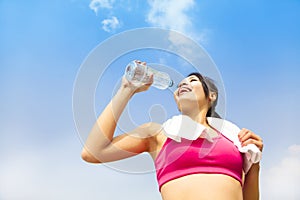 Young woman drinking water after fitness exercise