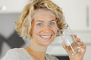 Young woman drinking water from glass indoors