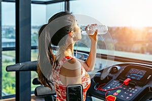 Young woman drinking water in the gym. Exercise concept