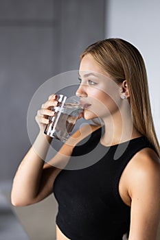 Young woman drinking water in the kitchen at home