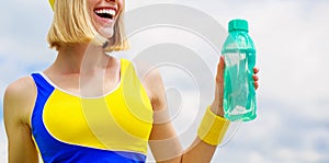 Young woman drinking water after run. Woman in sports wear is holding a bottle of water. Sports girl drinks water from a