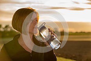 Young woman drinking water during sport outside