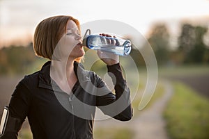 Young woman drinking water during sport outside