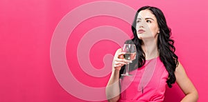 Young woman drinking wine on a solid background