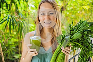Young woman drinks Celery Juice, Healthy Drink, bunch of celery on a wooden background