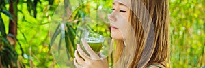 Young woman drinks Celery Juice, Healthy Drink, bunch of celery on a wooden background BANNER, LONG FORMAT