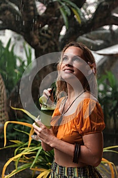 Young woman drinks cocktail in tropical rain