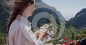 Young woman drinks coffee with Masca Gorge in background. Tenerife, Canary Islands, Spain