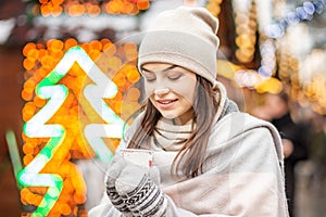 A young woman drinks coffee in the street in winter. Concept Lif