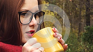 Young woman drinks hot tea from a mug to keep warm