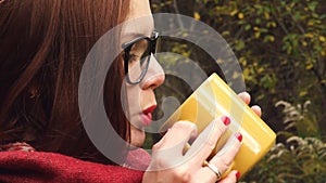 Young woman drinks hot tea from a mug to keep warm