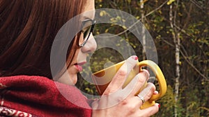 Young woman drinks hot tea from a mug to keep warm