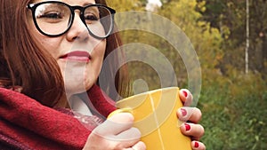 Young woman drinks hot tea from a mug to keep warm