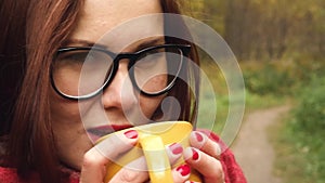 Young woman drinks hot tea from a mug to keep warm